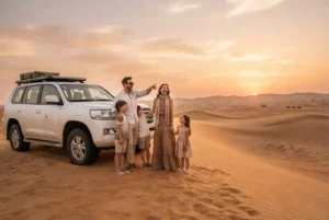 Family enjoying a Dubai desert safari beside a 4x4 vehicle at sunset